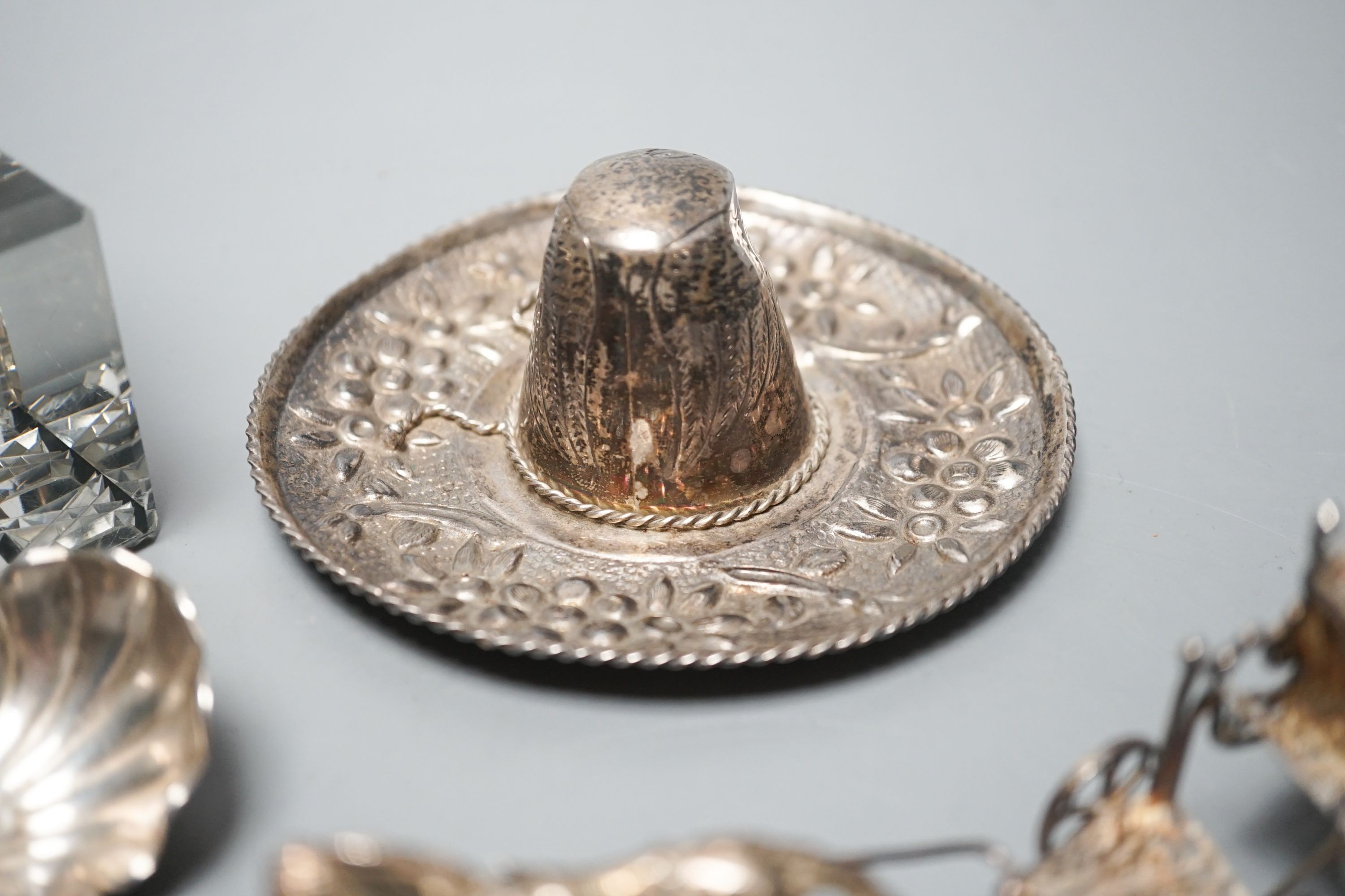A silver mounted glass inkwell, A Mexican white metal miniature sombrero, a white metal caddy spoon and a filigree horse and carriage.
